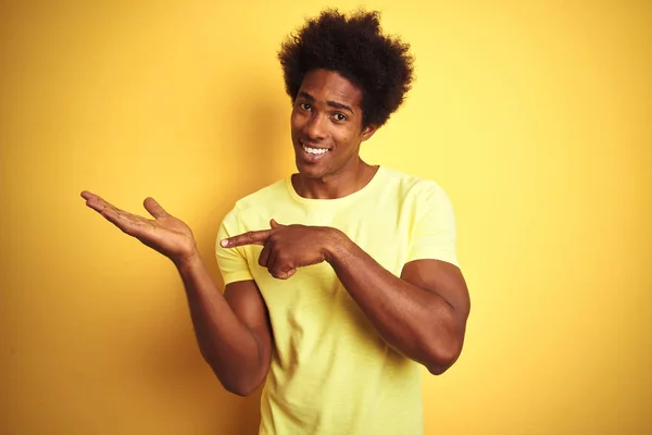 身穿T恤 头戴非洲裔美国人的黑人男子站在孤立的黄色背景上 惊讶地看着摄像机 同时用手和手指指指点点 — 图库照片