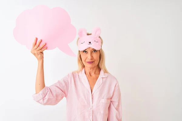 Middle age woman wearing sleep mask holding speech bubble over isolated white background with a confident expression on smart face thinking serious