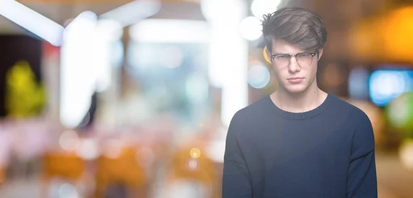 Young handsome man wearing glasses over isolated background skeptic and nervous, frowning upset because of problem. Negative person.