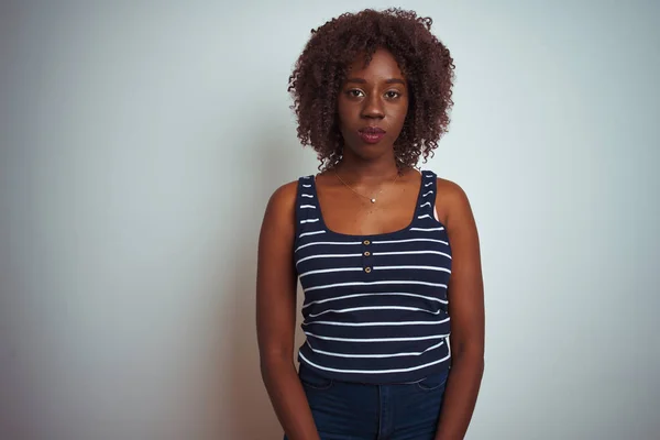 年轻的非洲裔妇女穿着条纹T恤 站在孤立的白色背景之上 脸上有着严肃的表情 简单而自然地看着相机 — 图库照片