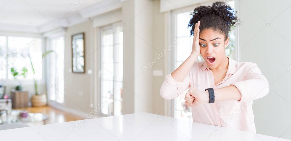 Wide angle of beautiful african american woman with afro hair Looking at the watch time worried, afraid of getting late
