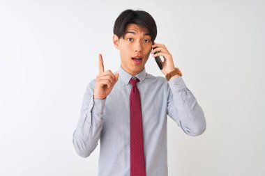 Çinli işadamı kravat takıyor ve akıllı telefondan konuşuyor. İzole edilmiş beyaz arka planda. Bir fikir veya soru işareti ile şaşırmış.