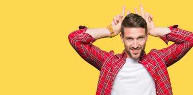 Yakışıklı adam rahat gömlek Posing komik ve deli parmaklarıyla başının üstüne tavşan kulakları giyen neşeli gülümseyen