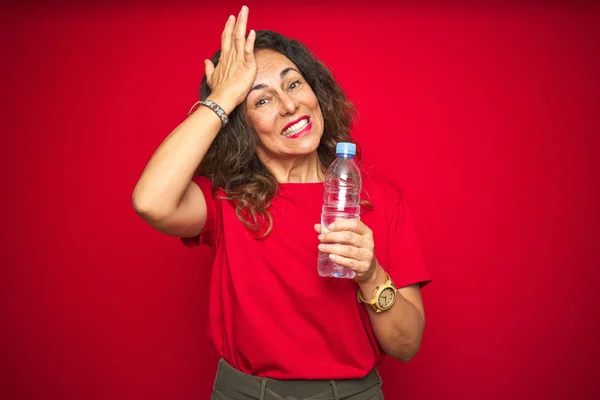 Seniorin Mittleren Alters Mit Plastikwasserflasche Über Rotem Isoliertem Hintergrund Gestresst — Stockfoto