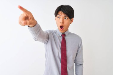 Soyutlanmış beyaz arka planda duran zarif kravat takan Çinli işadamı parmaklarıyla şaşırmış, ağzı açık ve şaşırmış bir ifade sergiliyor.