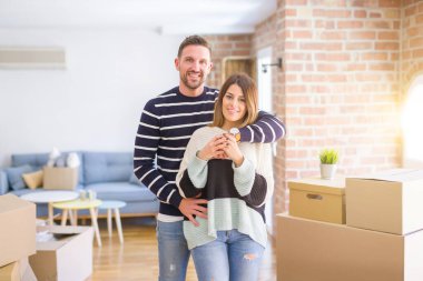 Karton kutular etrafında yeni evde sarılma genç güzel çift