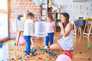 Genç, güzel öğretmen ve yeni yürümeye başlayan çocuklar anaokulundaki oyuncaklarla oynuyorlar.