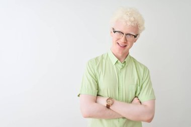 Yeşil tişörtlü ve gözlüklü genç albino bir adam izole edilmiş beyaz arka planda kolları çaprazlanmış kameraya bakarak gülümsüyor. Pozitif kişi.