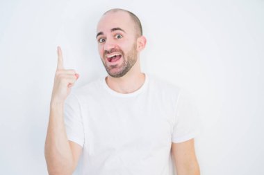 Beyaz izole edilmiş arka planda genç kel bir adam başarılı bir fikri işaret ediyor. Heyecanlı ve mutlu. Bir numara..
