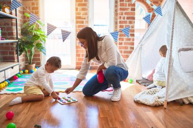 Güzel öğretmen ve çocuk matematik öğreniyor. Anaokulunda bir sürü oyuncağın etrafında sayılar bulmaca oyunu oynuyor.