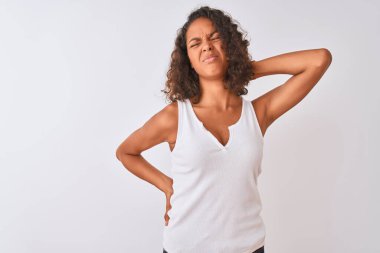İzole edilmiş beyaz arka planda dikilen sıradan tişört giyen genç Brezilyalı kadın boyun ağrısı çekiyor, eliyle boynuna dokunuyor, kas ağrısı çekiyor.