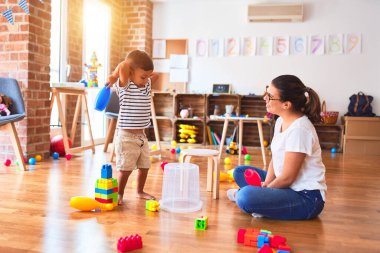 Anaokulunda trampet ve plastik sepet kullanan güzel bir öğretmen ve çocuk.