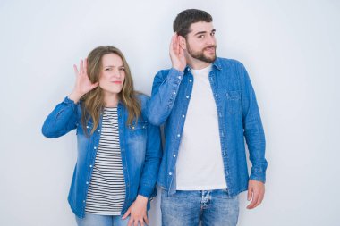 Genç ve güzel bir çift, beyaz soyutlanmış arka planda yan yana durup, el pençe divan gülümseyerek dedikodulara ve dedikodulara kulak veriyor. Sağırlık kavramı.