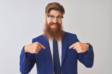 Genç Redhead İrlandalı işadamı elbise ve gözlük üzerinde izole beyaz arka plan üzerinde yüz gülümseme ile kendine güvenen görünümlü, parmaklarıyla gurur ve mutlu kendini işaret giyiyor.