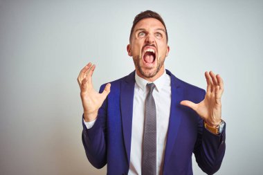 Genç yakışıklı iş adamı beyaz arka planda çılgın ve kızgın bir şekilde bağırıyor ve agresif bir ifade ve kolla bağırıyor. Hayal kırıklığı konsepti.