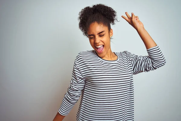 African american woman wearing navy striped t-shirt standing over isolated white background Dancing happy and cheerful, smiling moving casual and confident listening to music