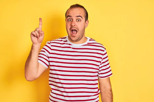 Jovem Vestindo Camiseta Listrada Casual Sobre Fundo Amarelo Isolado Apontando — Fotografia de Stock