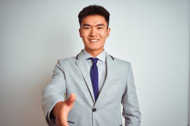 Asyalı Çinli işadamı takım elbise ve kravat takıp izole edilmiş sarı arka planda duruyor. Dostça bir selamlama ve hoş geldin hediyesi olarak gülümsüyor. Başarılı bir iş..