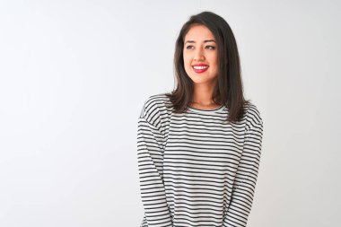 Çizgili tişört giyen genç, güzel Çinli bir kadın izole edilmiş beyaz arka planda durup yüzünde gülümsemeyle, doğal bir ifadeyle yan yana bakıyor. Kendinden emin gülen.