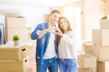 Güzel genç çift yeni bir eve aşık kalp sembolü ve şekli elleri ile gösteren gülümsüyor hareket. Romantik konsept.