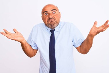 Orta yaşlı iş adamı, izole edilmiş beyaz arka plan üzerinde duran kravat takıyor. Kolları ve elleri havada, kafası karışık bir ifade takınıyor. Şüphe kavramı.