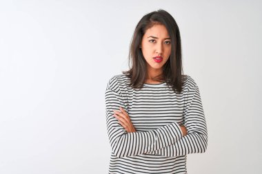 Çizgili tişört giyen genç, güzel Çinli bir kadın izole edilmiş beyaz arka plan üzerinde duruyor şüpheci ve gergin, yüzünde çapraz kollu tasvip etmeyen bir ifade. Negatif kişi.