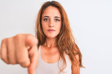 Genç kızıl saçlı kadın, izole edilmiş beyaz arka planda, parmağıyla kamerayı işaret ediyor ve sen, el işareti, ön taraftan pozitif ve kendinden emin bir hareket.