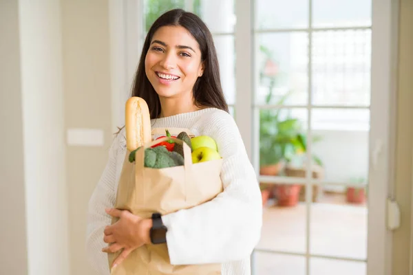 Mooie jonge vrouw glimlachend een papieren zak vol vers — Stockfoto