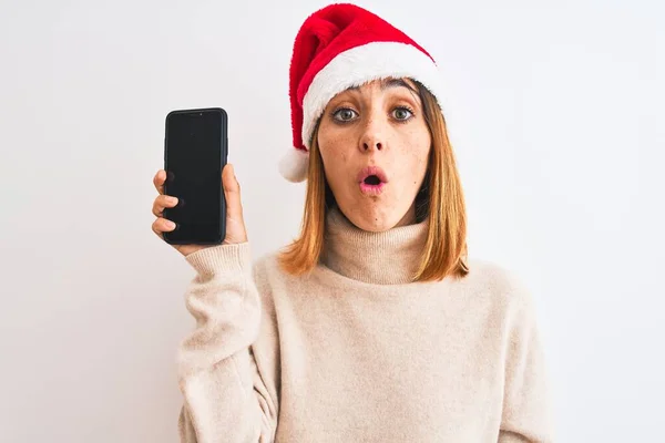 Όμορφη Κοκκινομάλλα Γυναίκα Φορώντας Χριστουγεννιάτικο Καπέλο Δείχνει Οθόνη Smartphone Φοβάται — Φωτογραφία Αρχείου