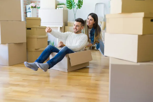 Young Couple Moving New Home Having Fun Riding Cardboard Boxes — Stock Photo, Image