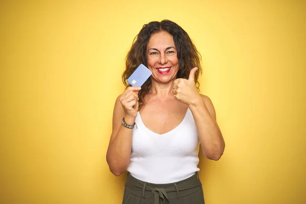 Starsza Kobieta Średnim Wieku Trzyma Kartę Kredytową Nad Żółtym Odizolowanym — Zdjęcie stockowe