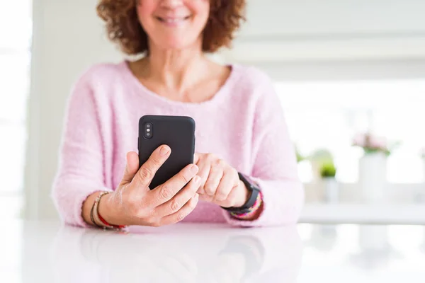 Primer plano de la mujer mayor utilizando el teléfono inteligente sobre la mesa blanca smili —  Fotos de Stock