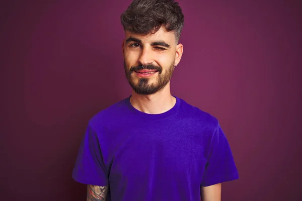 Jovem Com Tatuagem Vestindo Camiseta Sobre Fundo Roxo Isolado Piscando — Fotografia de Stock