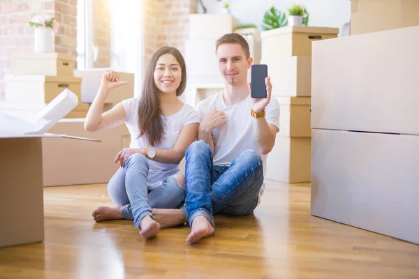 Hermosa Pareja Sentada Piso Sosteniendo Teléfono Inteligente Nuevo Hogar Alrededor — Foto de Stock