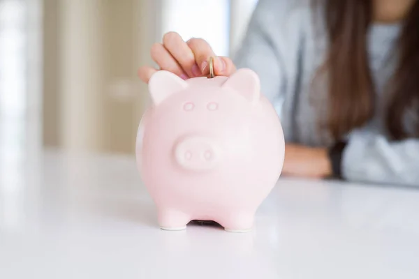 Jonge vrouw zet een munt binnen Piggy Bank als besparingen voor inve — Stockfoto