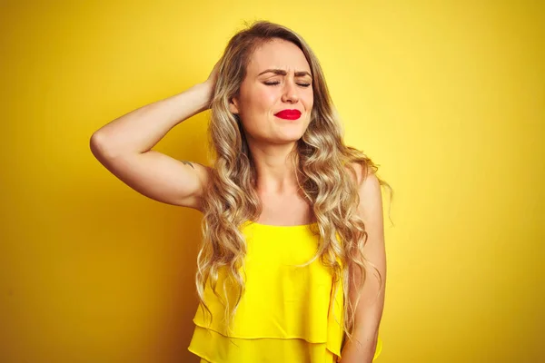Young attactive woman wearing t-shirt standing over yellow isolated background confuse and wonder about question. Uncertain with doubt, thinking with hand on head. Pensive concept.