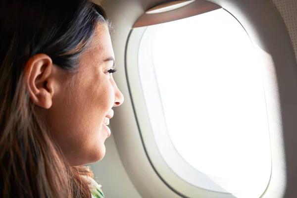 Young traveller woman sitting inside plane at the airport with sky view from the window