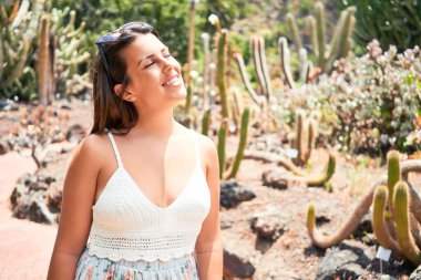 Güneşli bir yaz gününde yeşil kaktüs parkında mutlu ve neşeli gülümseyen güzel bir kadın.