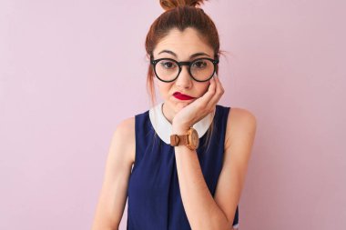 Kırmızı saçlı, atkuyruklu, zarif elbiseli ve gözlüklü, pembe arka planda, yorgun ve bunalımlı, kolları çapraz olan bir kadın..