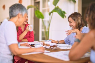 Genç ve güzel bir kız mutlu ve kendinden emin bir şekilde terasta oturmuş bir fincan kahve içiyor.