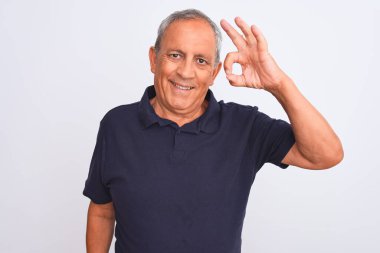 İzole edilmiş beyaz arka planda siyah polo giyen yaşlı gri saçlı adam el ve parmaklarıyla tamam işareti yaparken gülümsüyor. Başarılı ifade.