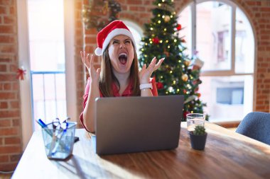 Noel 'de dizüstü bilgisayarla çalışan güzel bir kadın Noel Baba şapkası takıyor deli gibi bağırıyor ve agresif bir ifade ve kollarla bağırıyor. Hayal kırıklığı konsepti.