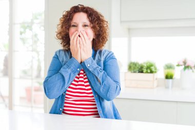 Kıvırcık saçlı, kot ceket giyen, kıkırdayan, kıkırdayan kıkırdayan, elleri, dedikoduları ve skandalları olan orta yaşlı bir kadın.