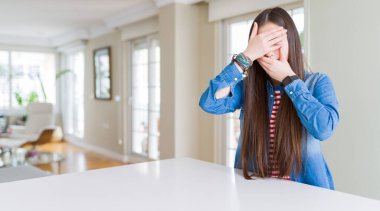 Uzun saçlı, güzel Asyalı kadın kot ceket giyiyor gözleri ve ağzı kapalı, şaşırmış ve şok olmuş. Duygularını gizliyor.