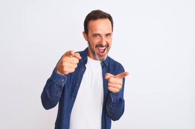 Mavi kot gömlek giyen orta yaşlı yakışıklı adam izole edilmiş beyaz arka plan üzerinde durmuş mutlu ve komik yüzlü parmakları kameraya doğrultuyor. İyi enerji ve titreşimler.