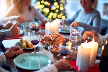 Aile ve arkadaşlar Noel arifesini geleneksel yemek ve dekorasyonla birlikte evde yemek yiyorlar. Hep birlikte masaya oturuyorlar.