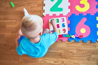 Anaokulunda oyuncaklarla oynayan beyaz bir çocuk. Anaokulu