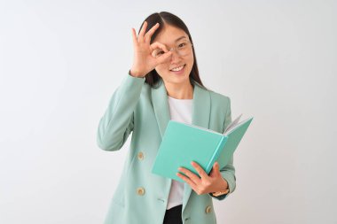 Genç Çinli öğrenci gözlük takıyor. İzole edilmiş beyaz arka planda kitap okuyor. Gülümsüyor.