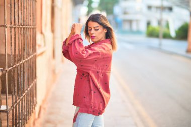 Kasabanın caddesinde duran kırmızı ceketli güzel bir kadın.