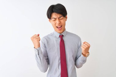 Soyutlanmış beyaz arka planda duran zarif kravat takan Çinli işadamı mutlu ve heyecanlı bir şekilde kollarını kaldırıp, gülümseyerek ve başarı çığlıkları atarak zafer jesti yapıyor. Kutlama konsepti.